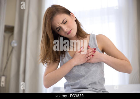 Giovane donna in pigiama avente un attacco di cuore Foto Stock
