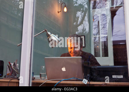 L'uomo visto attraverso una finestra sul laptop computer Apple Mac Foto Stock