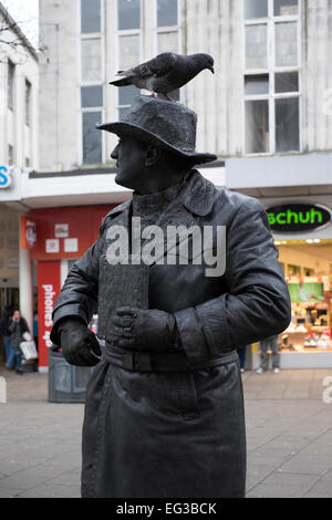 L'uomo tutti in abiti neri e oscurati la faccia di posa come una statua con un piccione sulla sua testa nella trafficata città di Portsmouth Inghilterra centrale Foto Stock