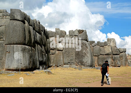 Uomo che cammina da muri in pietra di Sacsayhuaman fortezza Inca rovine, Cusco, Perù Foto Stock