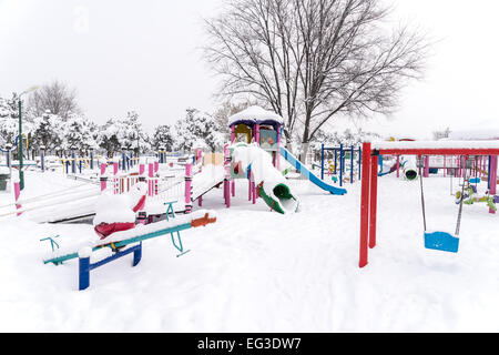 Parco giochi per bambini nel parco pubblico coperto con neve invernale Foto Stock