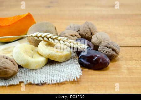 Fichi secchi, prugne, zucche con noci e kiwi su un tavolo di legno Foto Stock