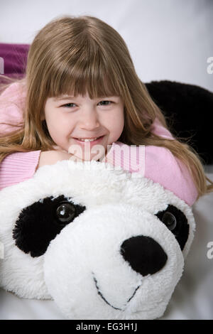 Bambina di cinque anni cuddling con un gigante, ripieni di orso panda Foto Stock