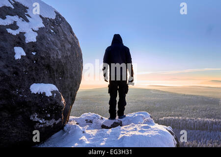 Silhouette di fotografo in piedi sulle montagne innevate in raggi di sunrise. Sudetes, Polonia, l'Europa. Straordinario Mondo. Foto Stock