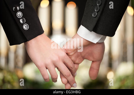 La religione, la morte e il dolor - coppia al funerale holding hands consolante ogni altro in considerazione della perdita Foto Stock