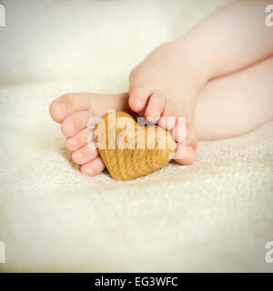 Piccola poco delicati piedi per tenere il cuore in legno Foto Stock