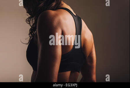 Montare e donna muscolare nel reggiseno per lo sport in piedi con la schiena verso la telecamera. Vista posteriore del fitness femmina con corpo muscoloso. Foto Stock