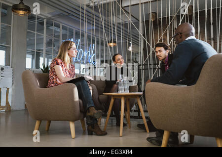 Diversi gruppi di giovani aventi un incontro nella lobby. I giovani dirigenti aziendali riunione in ufficio condividendo idee creative. Foto Stock