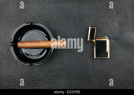 Golden accendino con un bicchiere di alcol e sigari giacente su una pelle  nera, può essere utilizzato come sfondo Foto stock - Alamy