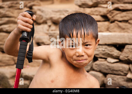 Giovane capretto nepalese in posa con arekking pole Foto Stock