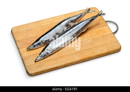 Congelati Saury Pacifico su un tagliere di legno, isolato su sfondo bianco Foto Stock