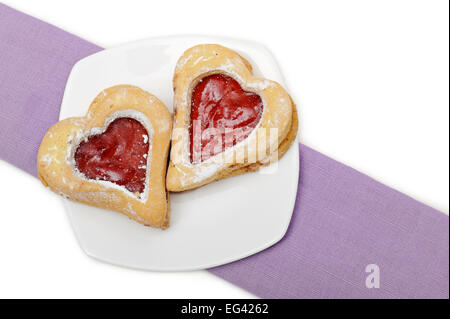 A forma di cuore cookie con confettura di fragole, sulla piastra Foto Stock