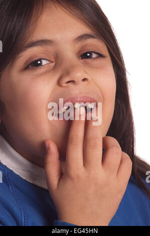 7 anno vecchia ragazza felice crescendo e fatto circa perdere ultimo traballanti rimanenti dente anteriore i denti di latte di cadere fuori Foto Stock