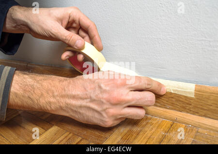 Protezione dei lavoratori batten stampaggio con del nastro adesivo protettivo prima della verniciatura a casa il lavoro di miglioramento. Foto Stock