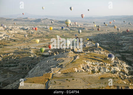 I palloni ad aria calda che si innalzano per oltre le grotte e formazioni di tufo nella luce del mattino, Nevsehir Provincia, Cappadocia Foto Stock
