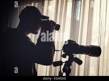 L'uomo con il binocolo e il controllo della telecamera qualcuno Foto Stock