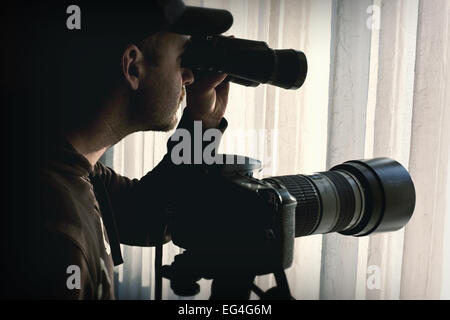 L'uomo con il binocolo e il controllo della telecamera qualcuno Foto Stock