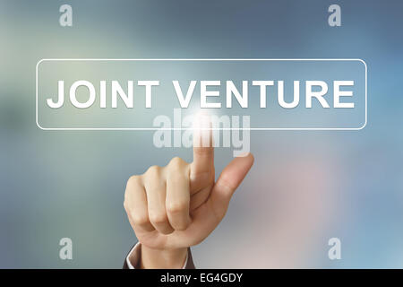 Business mano spingendo joint venture pulsante sullo sfondo sfocato Foto Stock