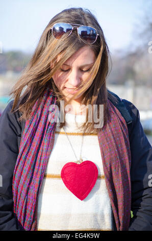 Giovani Caucasian brunette con un cuore intorno al suo collo, all'aperto Foto Stock