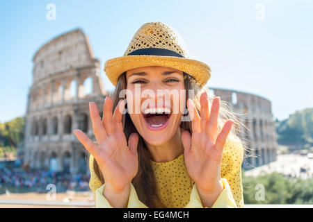 Felice giovane donna urlando attraverso il megafono mani sagomata nella parte anteriore del Colosseo a Roma, Italia Foto Stock