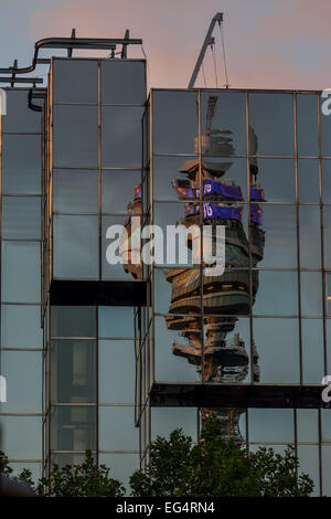 Torre Telecom riflessa e distorta in un edificio di vetro Foto Stock