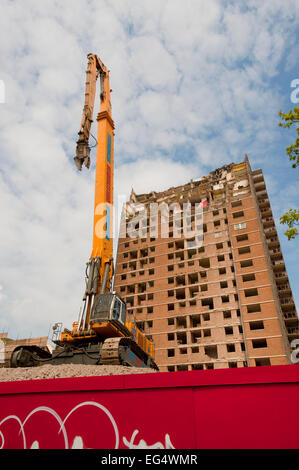 Una demolizione gru si siede di fronte a un parzialmente demolito a torre a Ibrox, vicino Govan nel sud ovest di Glasgow. Foto Stock