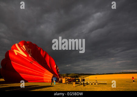 Il lavoro di squadra preparazione per tethered mongolfiera contro il cielo drammatico, south Oxfordshire, Inghilterra Foto Stock