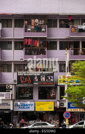 Facciata di un tipico appartamento blocco in Little India, Kuala Lumpur, Malesia, con cartelli pubblicitari e lavaggio appesi per asciugare o Foto Stock