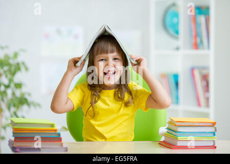 Studente kid con un libro sulla sua testa Foto Stock