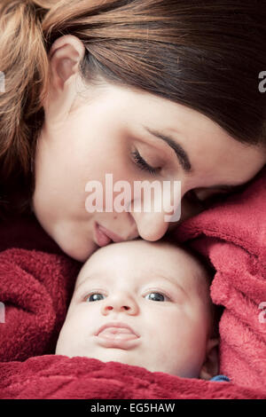 Madre con la sua giovane baby coccole e baciare lui sulla fronte. La paternità, l'amore. Foto Stock