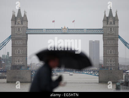 Regno Unito, Londra : un uomo di battaglie il forte vento con il suo ombrello come egli cammina attraverso un ponte nel centro di Londra il 12 febbraio 2014. Foto Stock