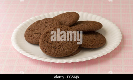 Biscotti al cioccolato su un piatto di carta in cima a un tavolo a scacchiera panno. Foto Stock