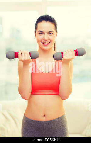 Sorridente ragazza adolescente esercizio con manubri Foto Stock