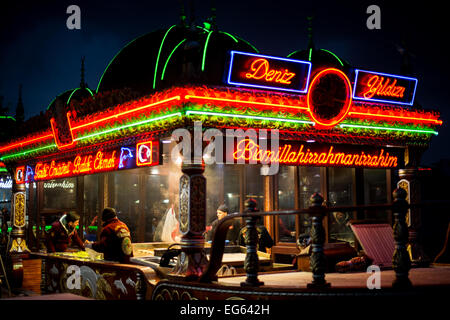 Ristoranti galleggianti Balik Ekmek Eminonu Istanbul Turchia // ISTANBUL, Turchia - le barche illuminate balik ekmek servono tradizionali panini di pesce ai commensali lungo il lungomare di Eminonu vicino al ponte Galata. Questi ristoranti galleggianti, conosciuti localmente come balıkçı tekneleri, offrono sgombri alla griglia serviti con pane bianco con cipolle e lattuga come popolare cibo di strada. Le barche decorate con gusto presentano motivi in stile ottomano e rimangono permanentemente ormeggiate lungo lo storico lungomare del Corno d'Oro. Eminonu funge da importante terminal dei traghetti e da quartiere commerciale che collega il lato europeo e asiatico Foto Stock
