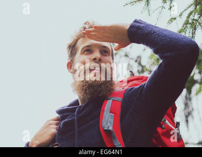 Uomo sorridente con la barba e zaino escursionismo Foto Stock