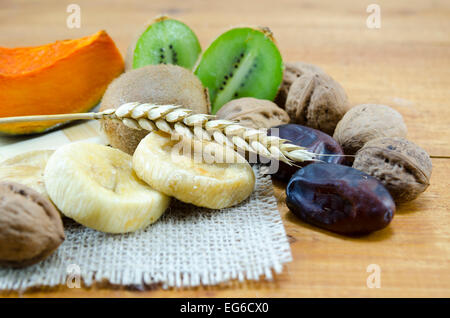 Fichi secchi, palme, zucche con noci e kiwi su un tavolo di legno Foto Stock