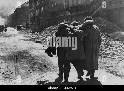 Sovietica ferito (Russo) soldato aiutato da due compagni in una strada piena di macerie, Vienna. 1945 Guerra Mondiale 2 fotografia di Foto Stock