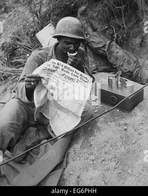 African American radio operatore legge news mentre mangiando razioni alimentari vicino Sangju, Corea. Il 9 agosto 1950. Guerra di Corea, 1950-1953. Foto Stock