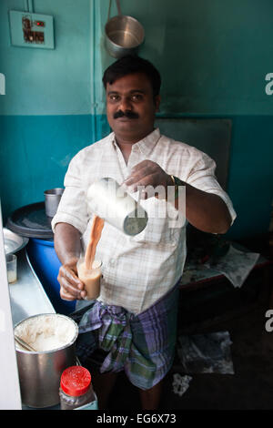 "Chai wallah' o tè tè - uomo versa il suo chai tra bicchieri prima di servire ai clienti, Kumily Kerala, nell India meridionale Foto Stock