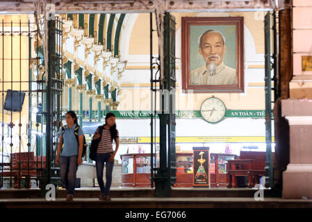 Due donne sono lasciando un ufficio postale in Ho Chi Minh City il 21 novembre 2014. Un ritratto di Ho Chi Minh è appeso alla parete. Foto Stock