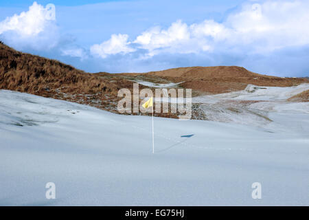Bandiera gialla su una coperta di neve del campo da golf links in Irlanda in inverno Foto Stock