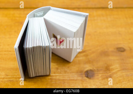 Piccolo libro aperto con una forma di cuore su una pagina, colpo contro una superficie in legno Foto Stock