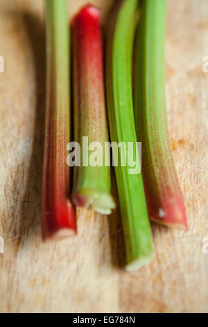 Quattro gambi di rabarbaro su un tagliere di legno Foto Stock