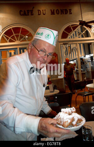 Cameriere che serve beignets al Cafe Du Monde nel Quartiere Francese, New Orleans, Louisiana, Stati Uniti d'America. Foto Stock