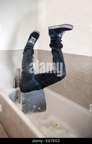 Un uomo sembra di essere risucchiato verso il basso scarico nel bagno mentre un anatra di gomma si affaccia su - un'immagine concettuale per lavello o nuotare Foto Stock