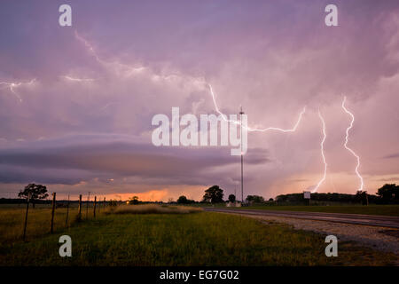 Cloud to ground and anvil crawling lightning bolts illuminate a decaying evening supercell thunderstorm in central Texas Foto Stock