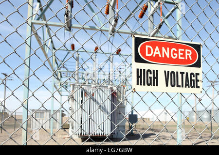 Un segno hconcept elettricità Pericolo alta tensione voltageigh segno di avvertimento sul recinto intorno a una sottostazione elettrica. Foto Stock