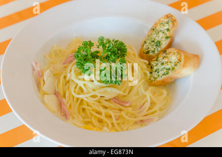 Spaghetti alla carbonara con lardo e aglio pane sul piatto Foto Stock