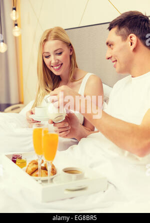 Coppia sorridente avente la colazione a letto in hotel Foto Stock