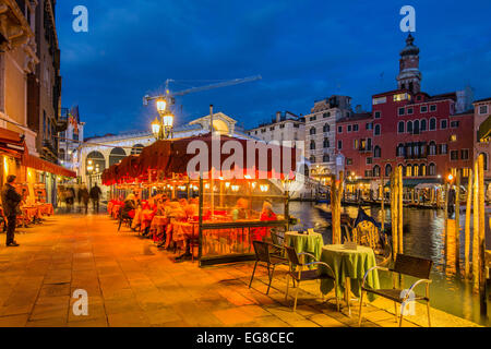Vista notturna di un outdoor cafe ristorante lungo il Canal Grande con il ponte di Rialto, dietro, Venezia, Veneto, Italia Foto Stock